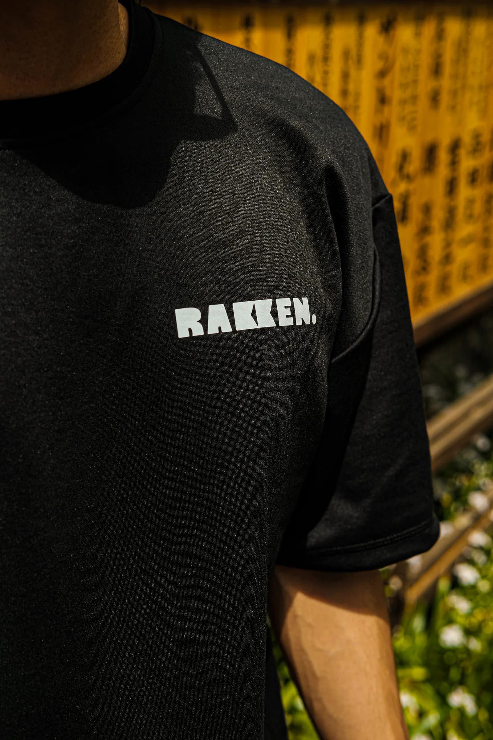 Detail logo RAKKEN di bagian depan kaos hitam