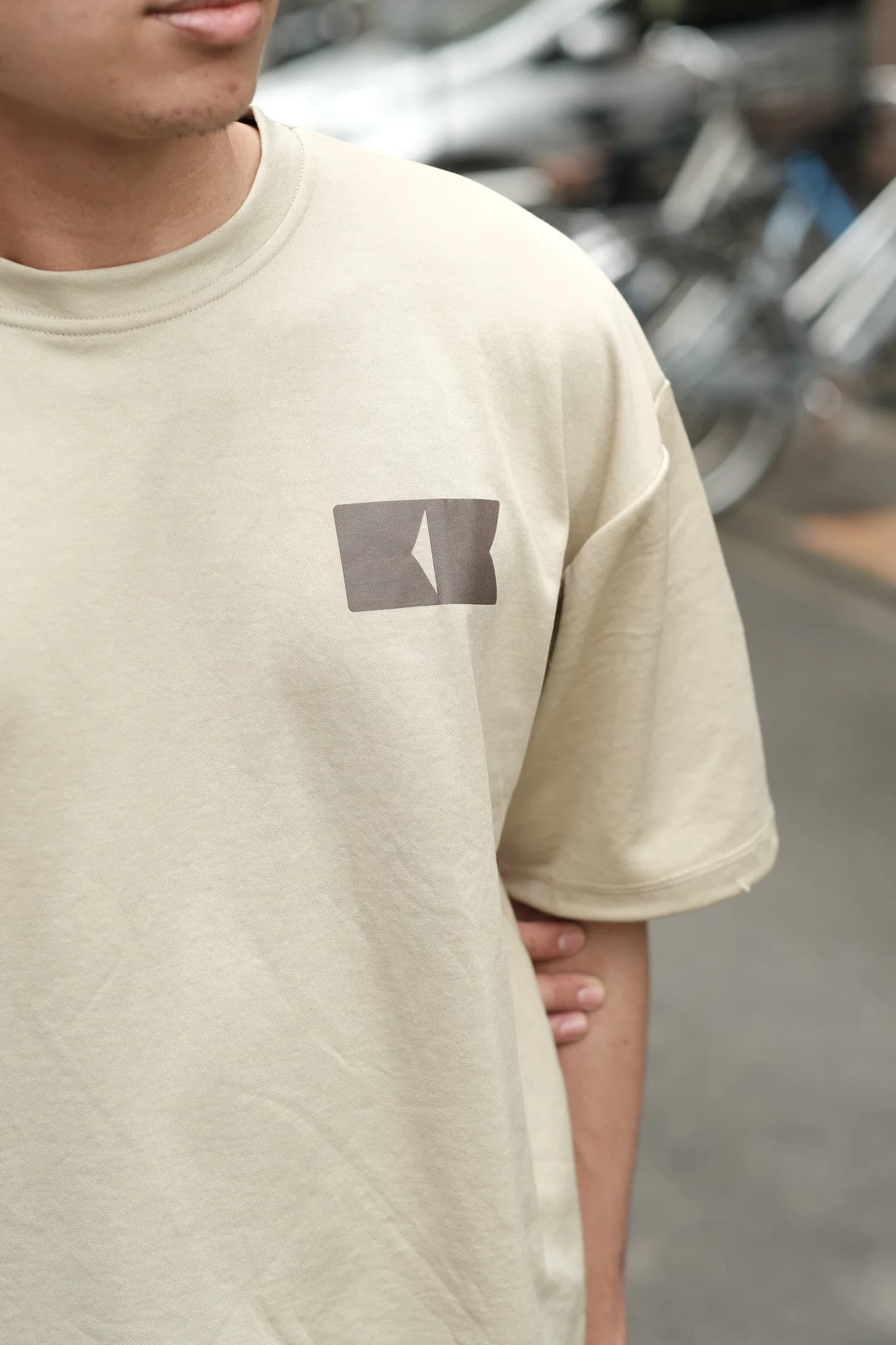 Detail logo di bagian depan kaos cream RAKKEN